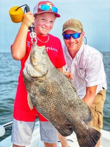 Boy holding up a large Tripletail with his brother.